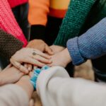 Ενωμένα χέρια ανθρώπων με διαφορετικούς τόνους δέρματος, συμβολίζοντας την ποικιλομορφία, την ισότητα και τη συμπερίληψη στον εργασιακό χώρο